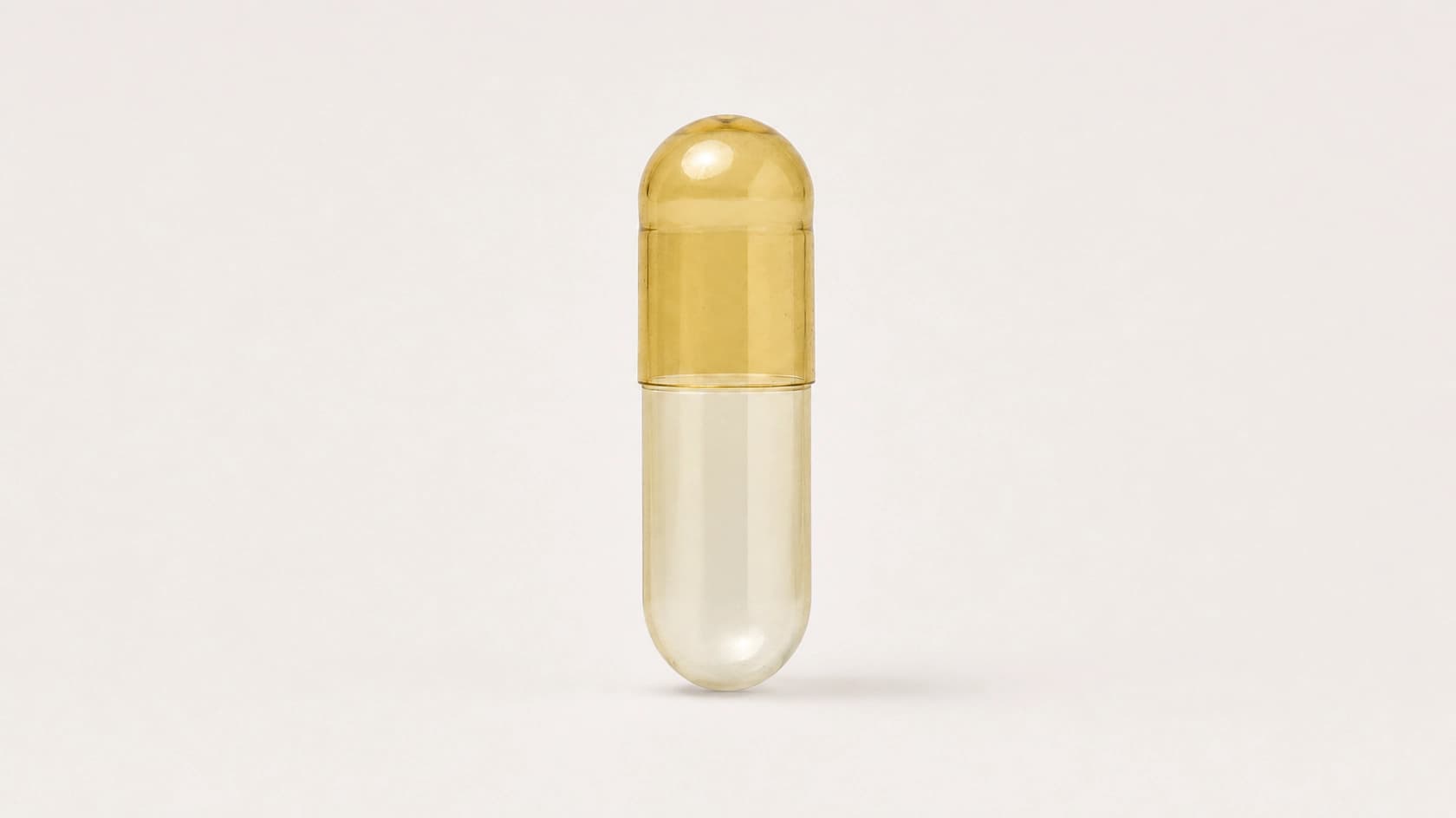 Upright empty size 00 gelatin capsule with a translucent amber cap and clear body