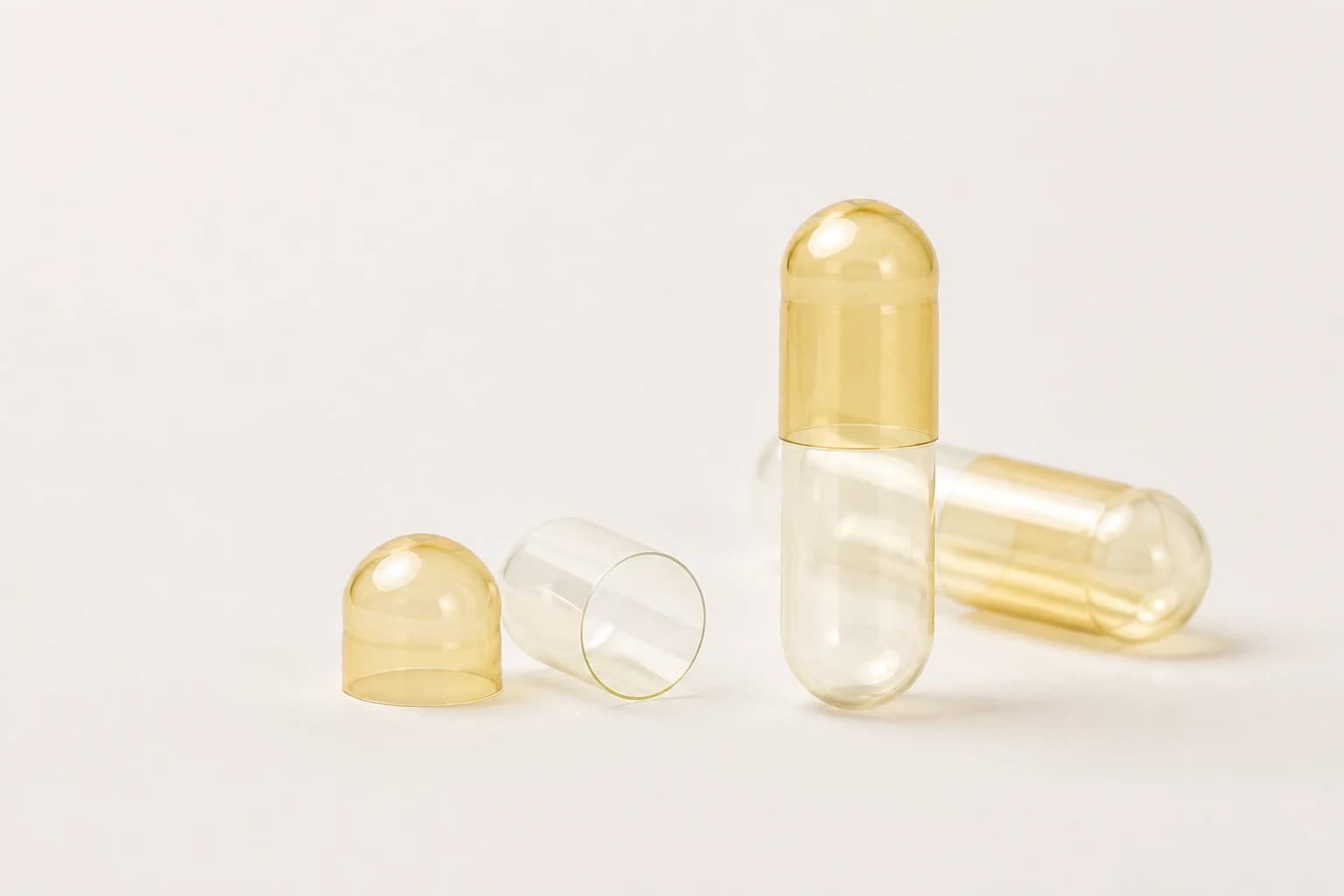 Empty clear and pale-amber gelatin capsule shells in a studio setting