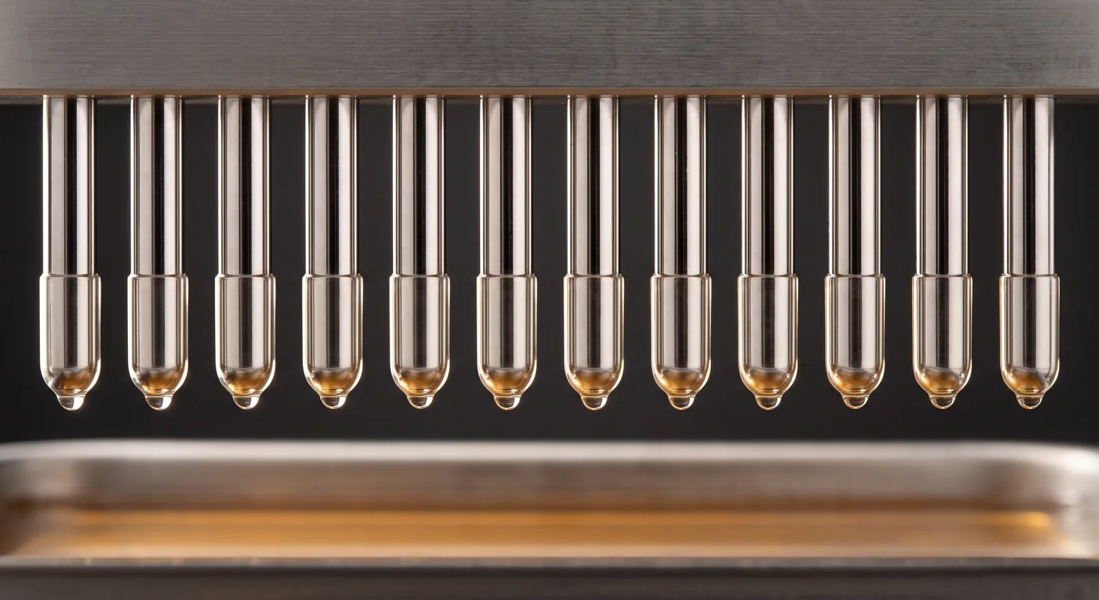 Coated steel dipping pins above a liquid bath.