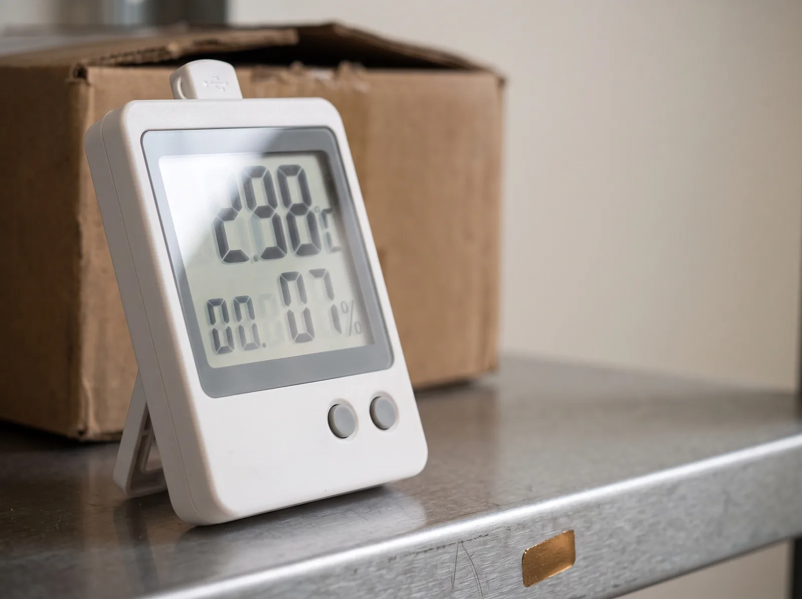 A temperature and humidity logger beside a capsule carton.