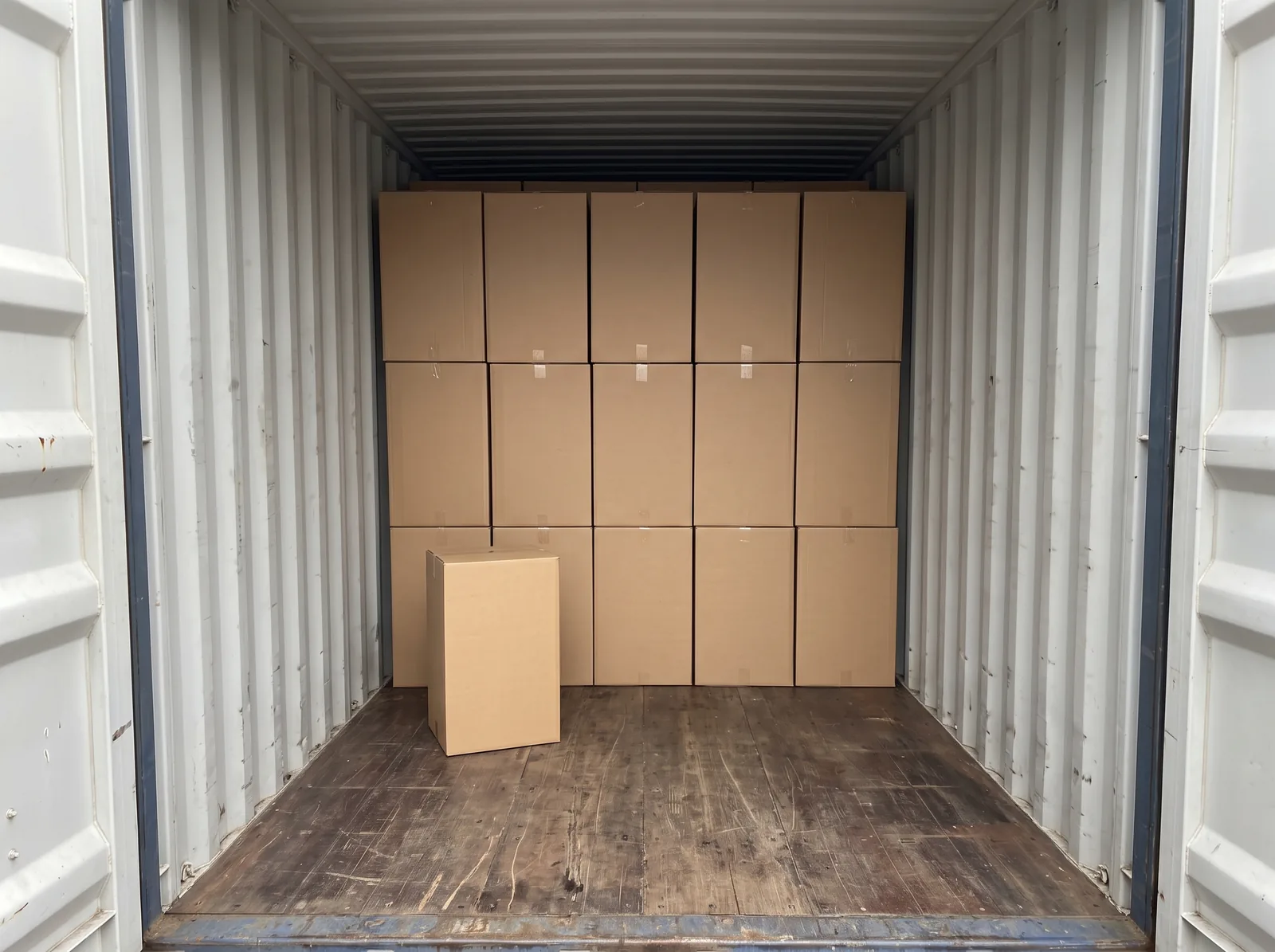 Cardboard cartons stacked directly on the floor of a shipping container.