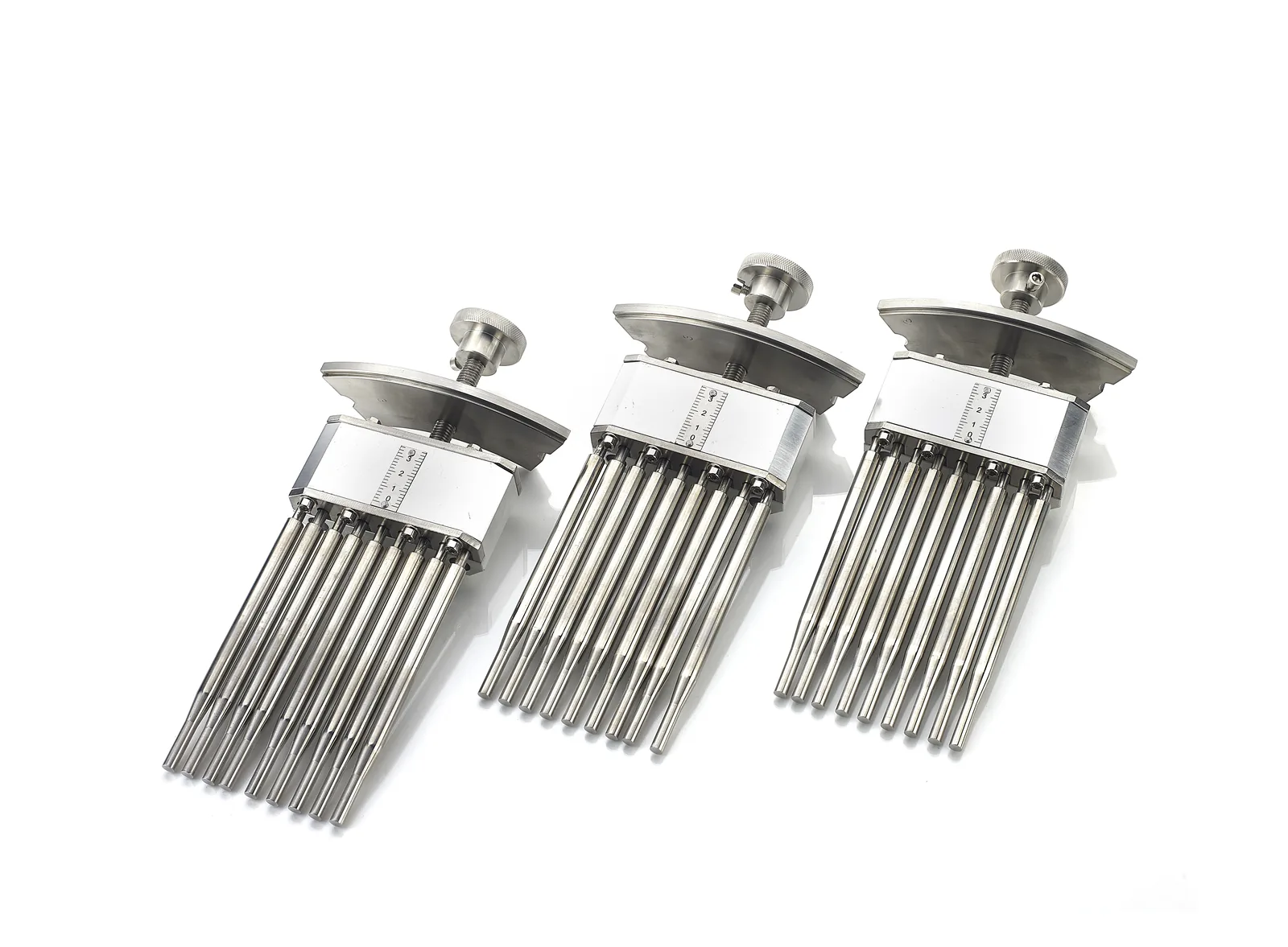 Three metal capsule tooling assemblies with rows of pins, in different sizes.
